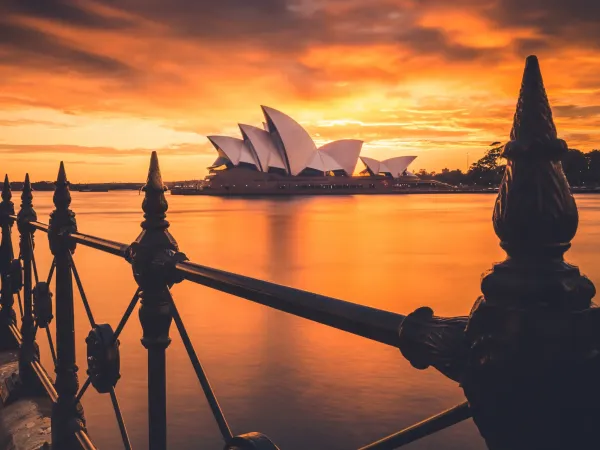 Sydney Opera House at sunset seen from a harbour railing